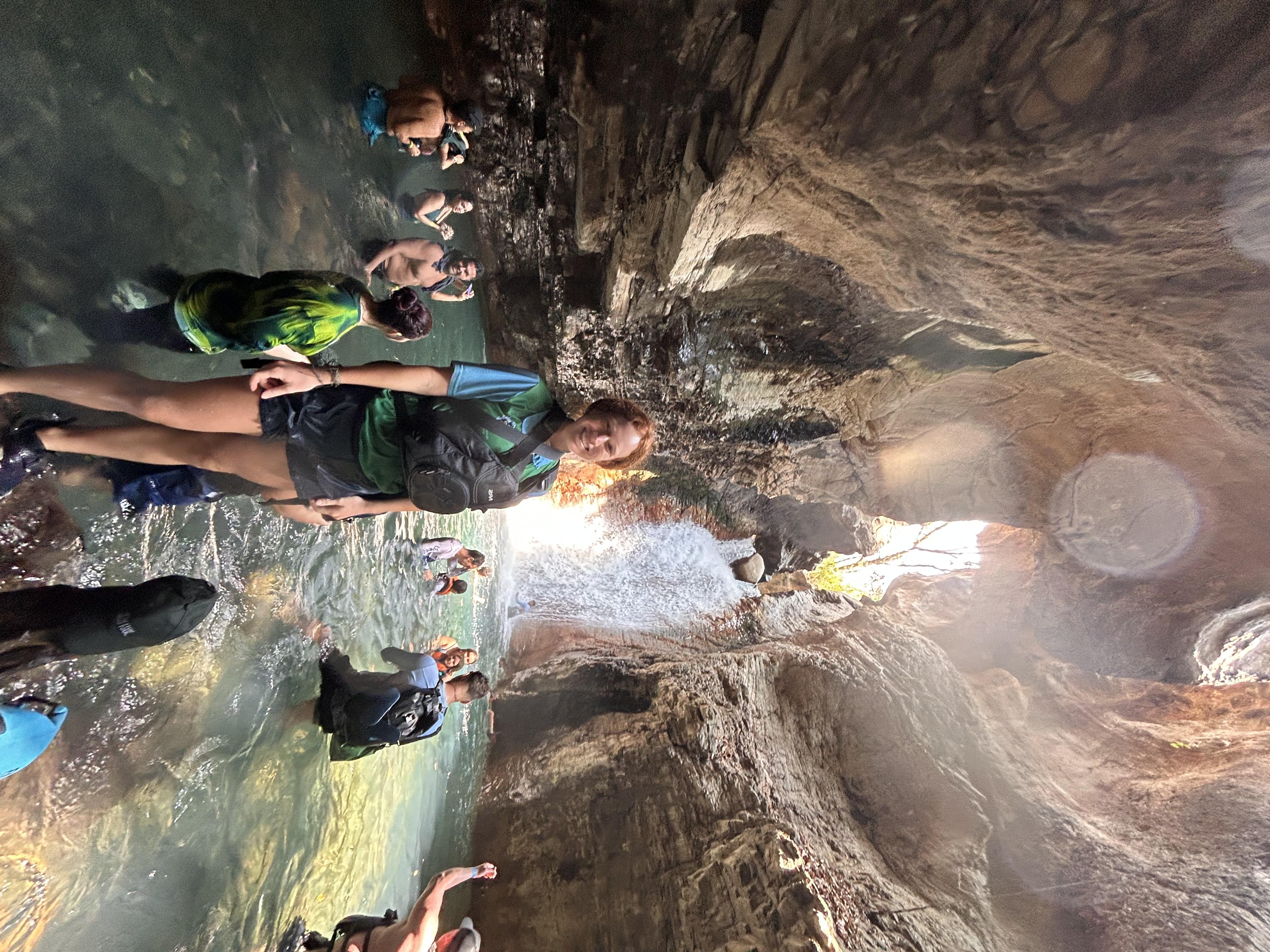 Woman tour guide posing by water in a cave